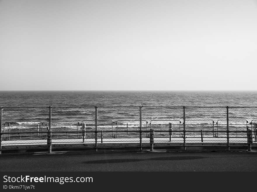 Grayscale Photography of Fence Beside Ocean