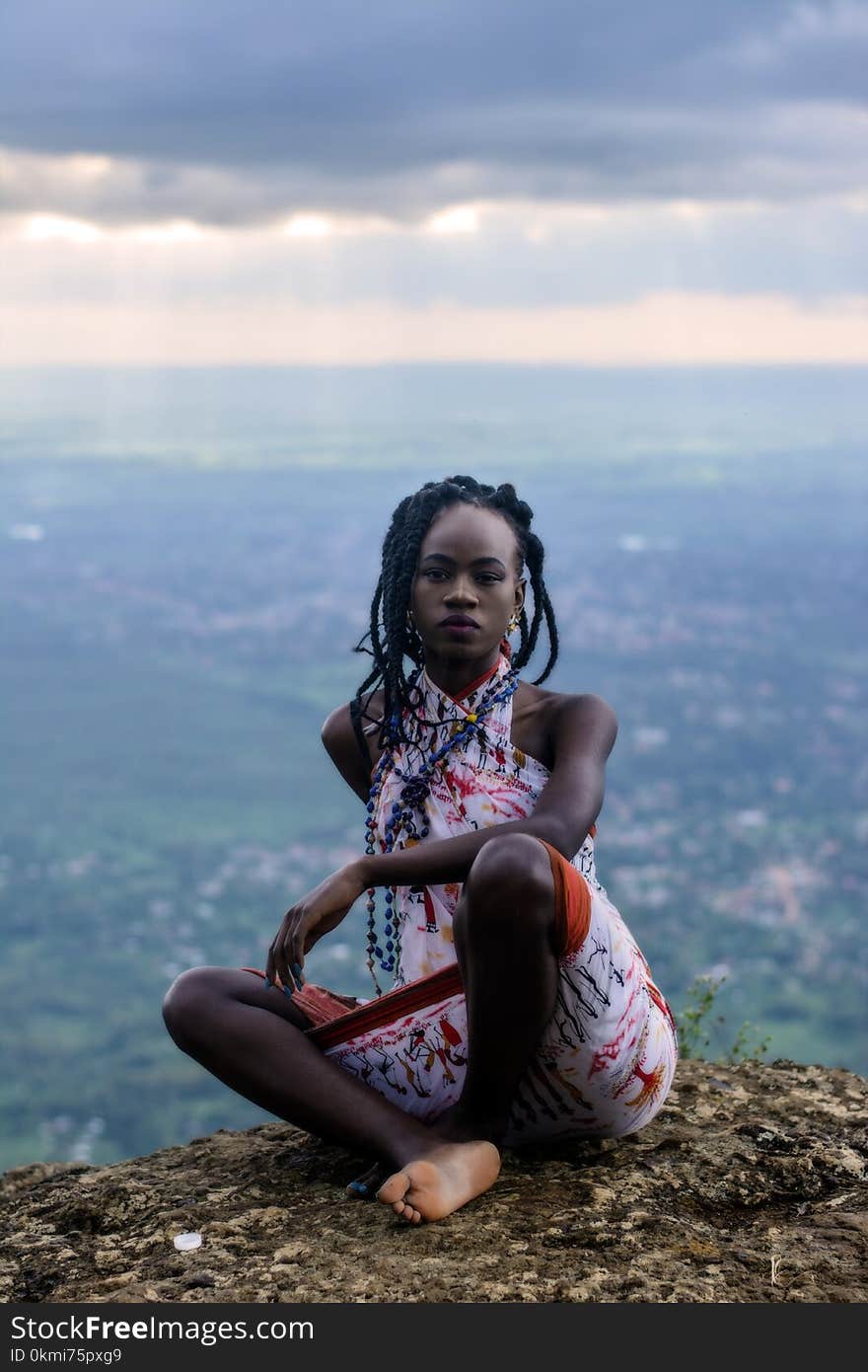 Woman Sitting on Ground and Village at Distance