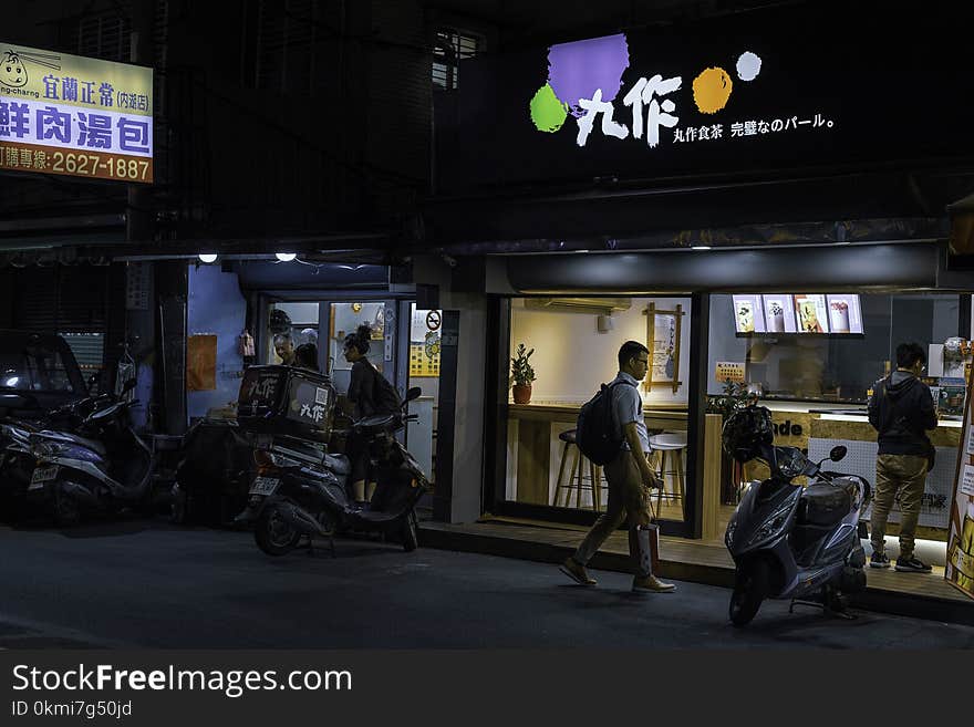 Man Standing Near White Motor Scooter at Night