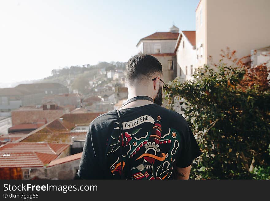 Man Wearing Black T-shirt Standing Near White Concrete Houses