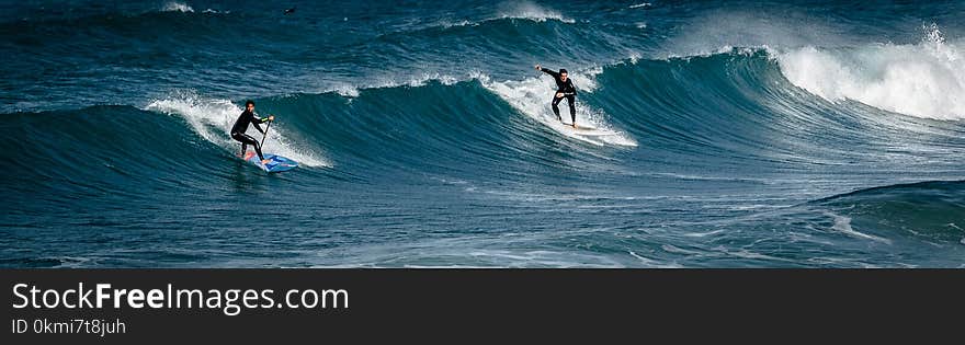 Two Surfers Gliding on Body of Water