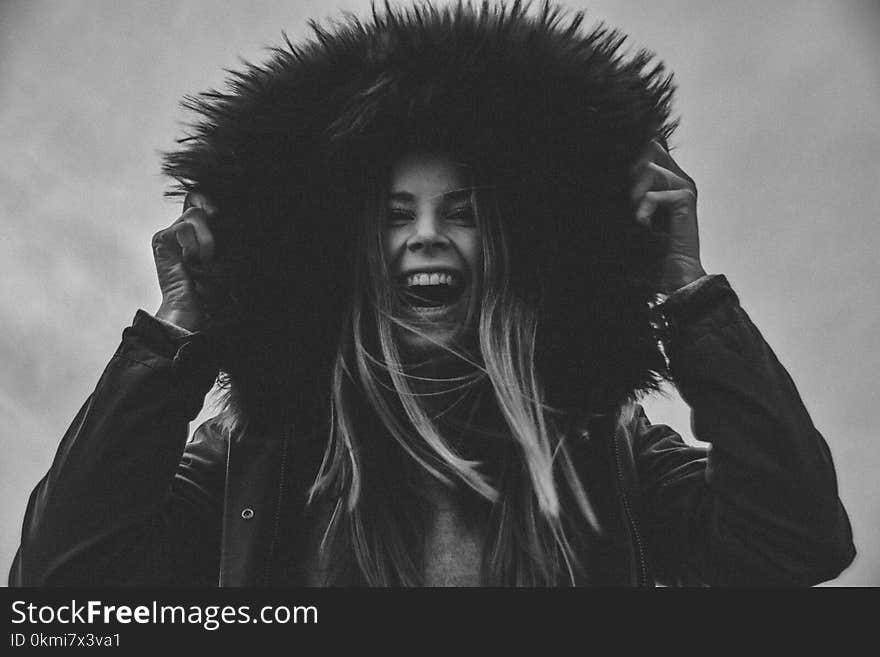 Grayscale Photo of Laughing Woman Holding Her Hat