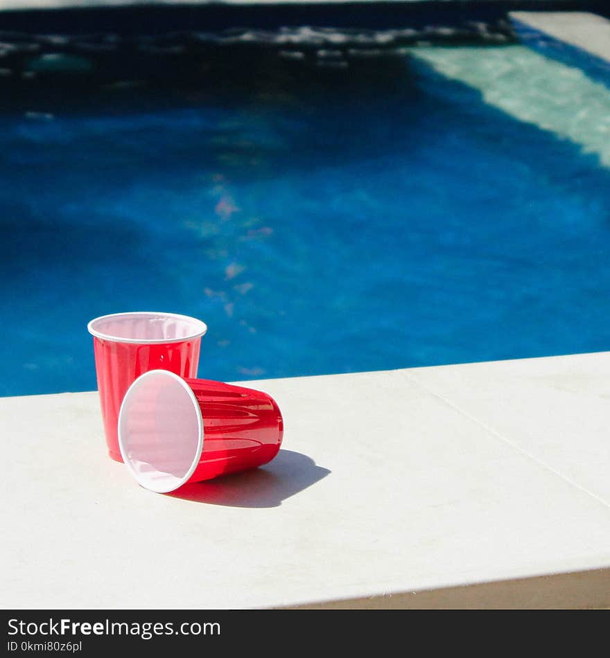 Two Red-and-white Disposable Cups on Gray Ceramic Tiles Photo