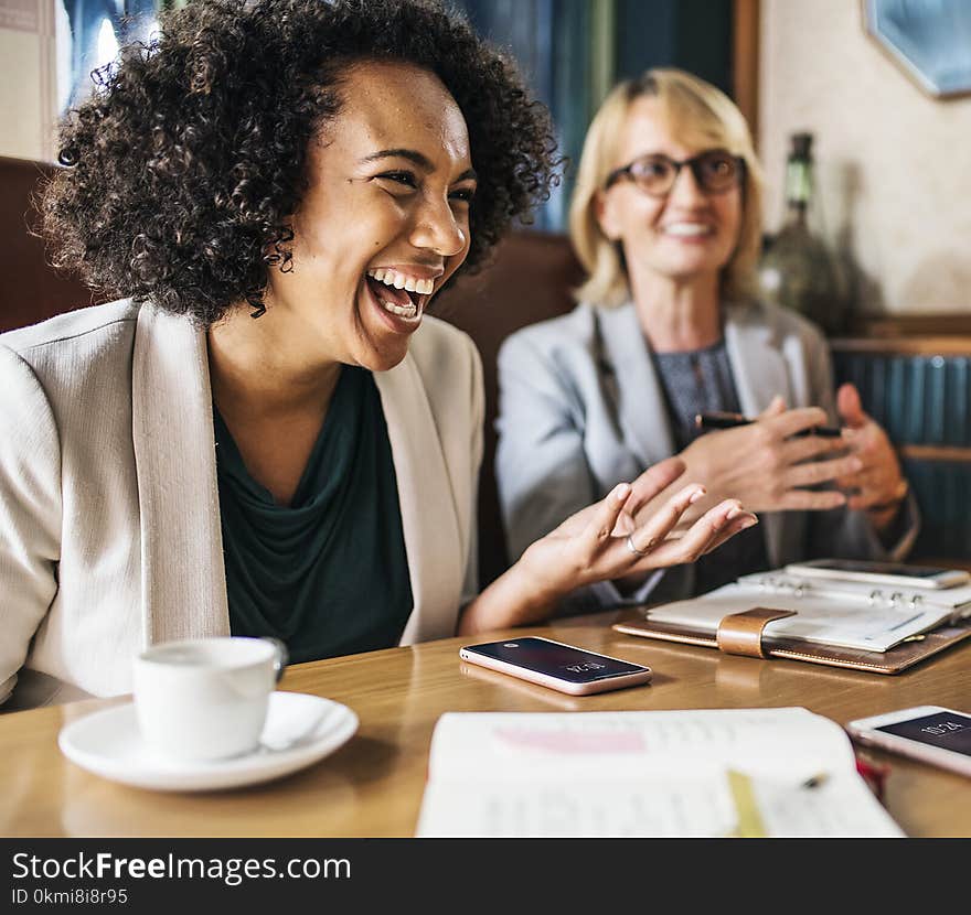 Woman in Formal Coats Sitting in Front of Table