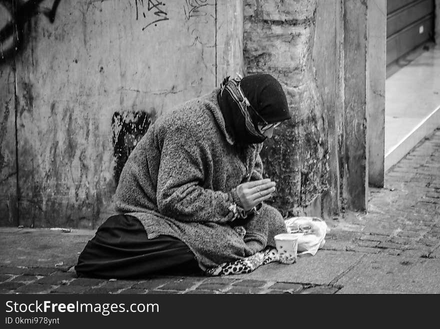 Grayscale Photography of Man Praying on Sidewalk With Food in Front