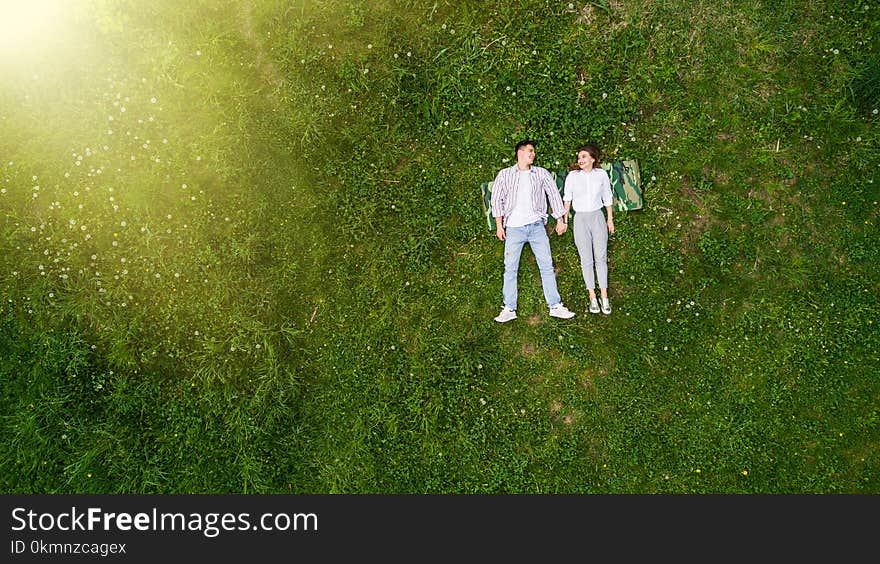 Beautiful in love young couple lying on the grass, view from above