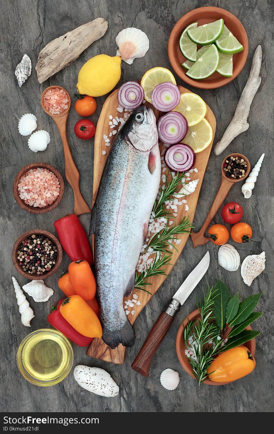 Healthy heart food with rainbow trout fish, seasoning, herbs, vegetables and olive oil on marble background. High in omega 3 fatty acids.