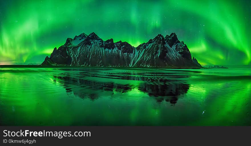 Aurora reflections on Stokksnes black beach with Vestrahorn mountains in center, Iceland. Aurora reflections on Stokksnes black beach with Vestrahorn mountains in center, Iceland