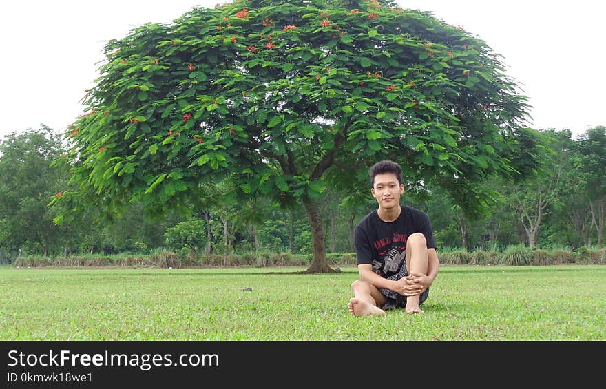 Man in Black Shirt Sitting on Grass Field