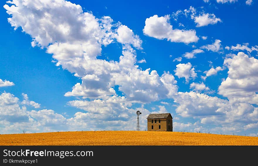 Brown Concrete House Near Tower Under Cloudy Sky