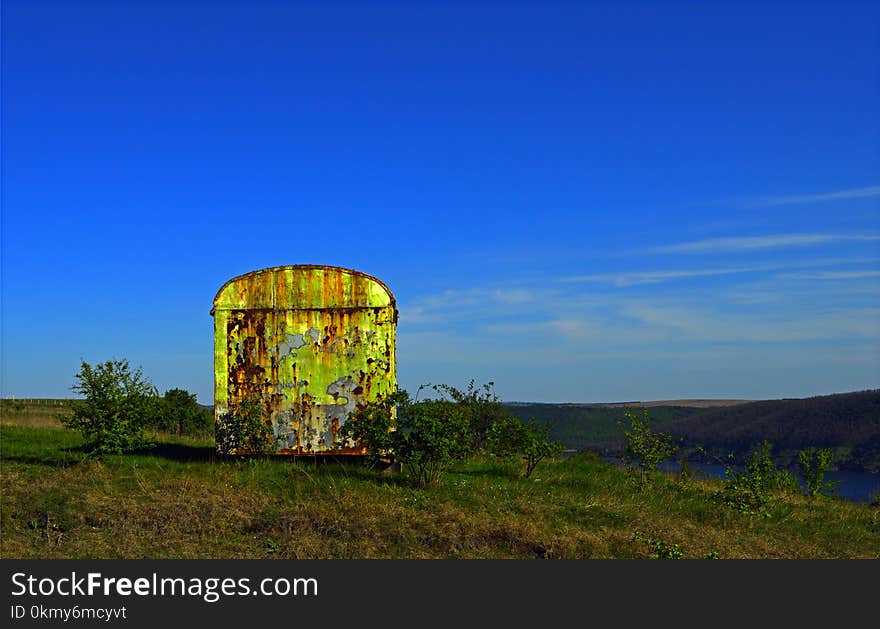 Iron rusty container on the meadow in the grass and bushs