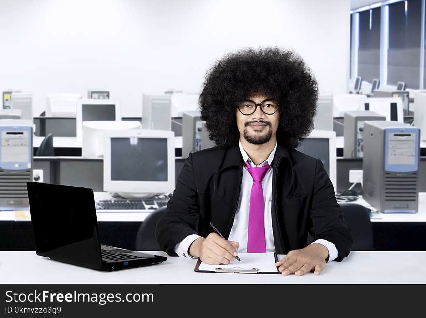 Afro businessman working in the office while wearing glasses and smiling at camera. Afro businessman working in the office while wearing glasses and smiling at camera