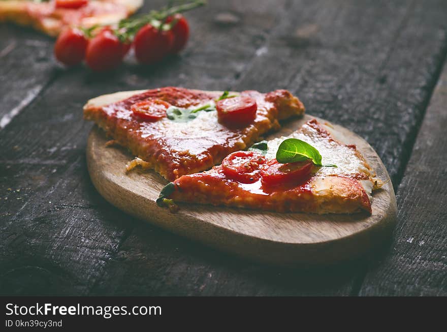 Italian food, cuisine. Margherita pizza on a black, wooden table with igredients like tomatoes, salad, cheese, mozzarella, basil. Delicious homemade food