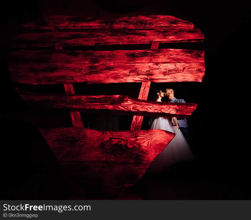 Wedding in the style of rock. Rocker or Biker wedding. Guys with stylish leather jackets. It`s a rock`n`roll baby. Sweet couple in a photo studio. Steep shooting in a wooden location. Around the bulb of warm light. A huge wooden heart.