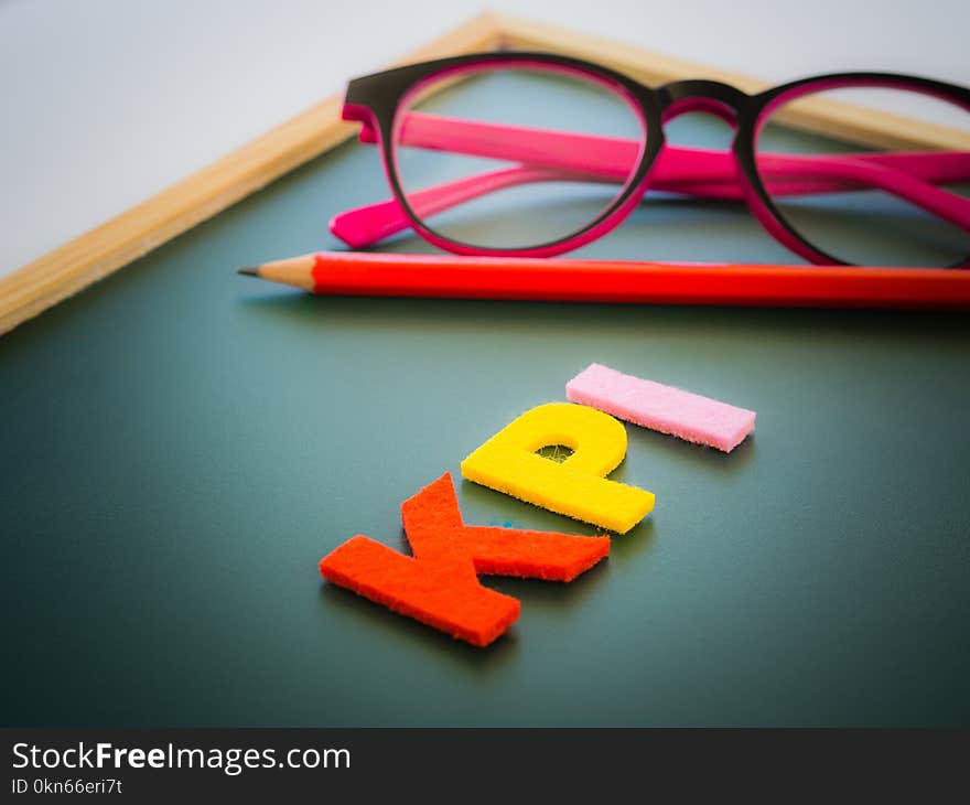 KPI alphabet with red pencil and pink glasses put on white table background