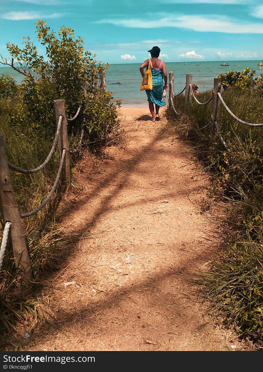 Woman Wearing Blue Scarf Walking on Pathway