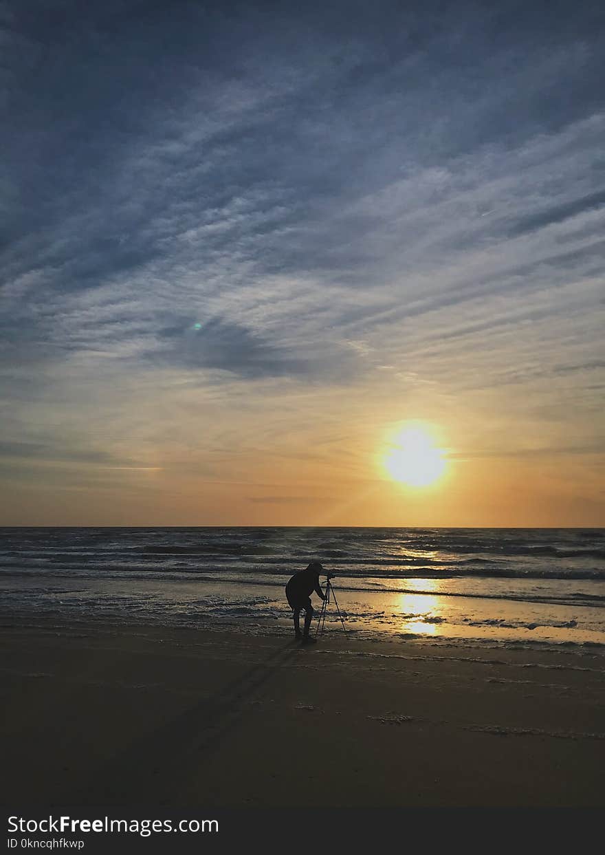 Silhouette Photo of Person Placing Tripod Stand on Seashore