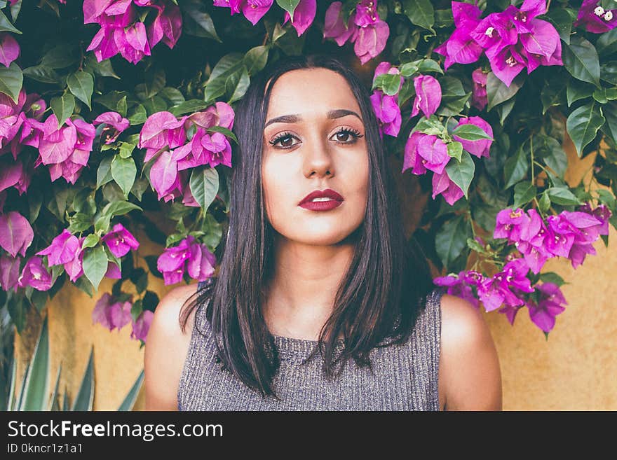 Woman in Gray Scoop-neck Sleeveless Top Standing in Front of Purple Flowers