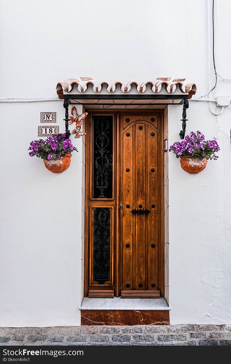 Brown Wooden Door Beside Two Purple Petaled Flowers