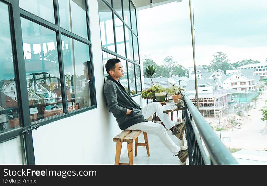 Man in Black Jacket Sitting on Bench Outdoors