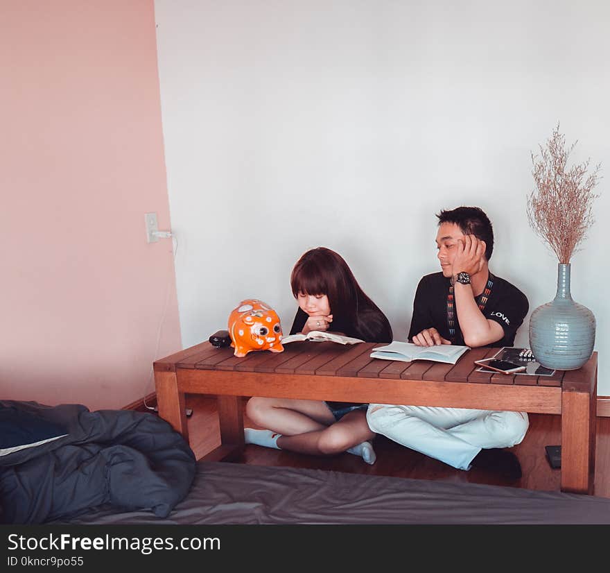 Girl and Boy Sitting in Front of Brown Wooden Coffee Table