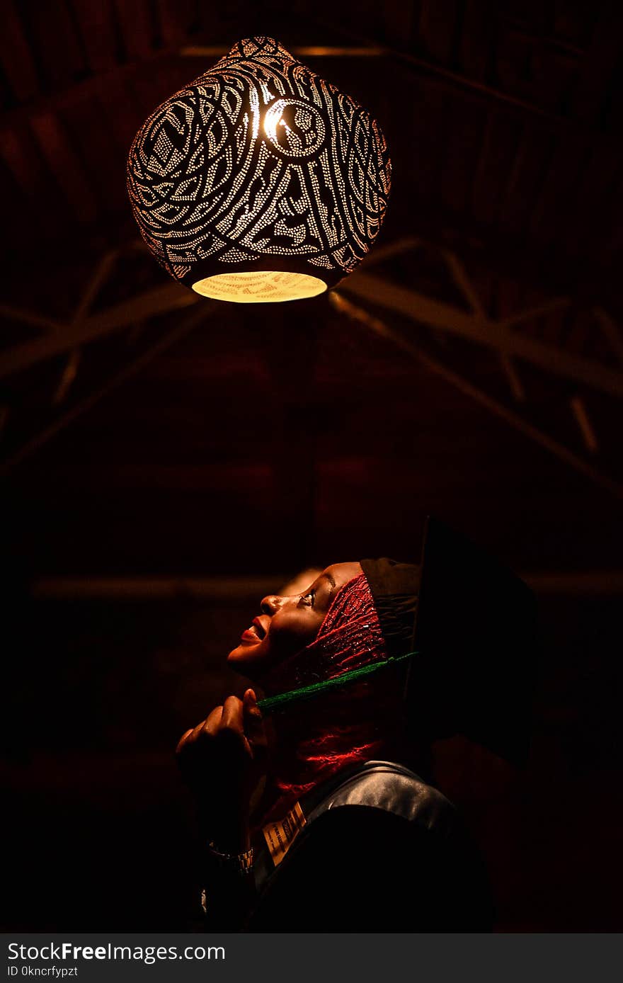 Woman Looking Upwards Toward Pendant Lamp