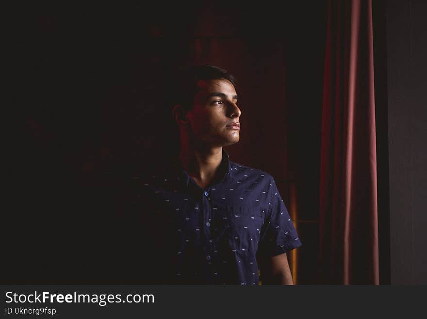 Man in Black Button-up Shirt Standing Beside Red Curtain