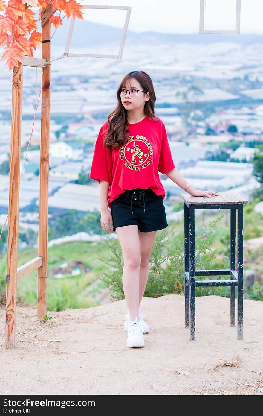 Woman in Red T-shirt and Black Shorts Near on Metal Stool