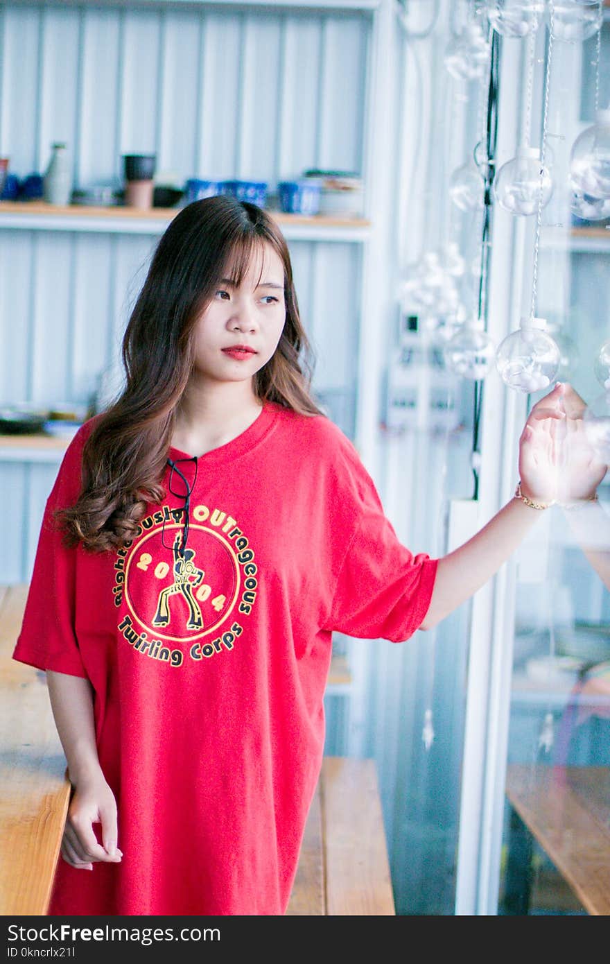 Woman Wearing Red Shirt Standing Near Glass Hanging Decor