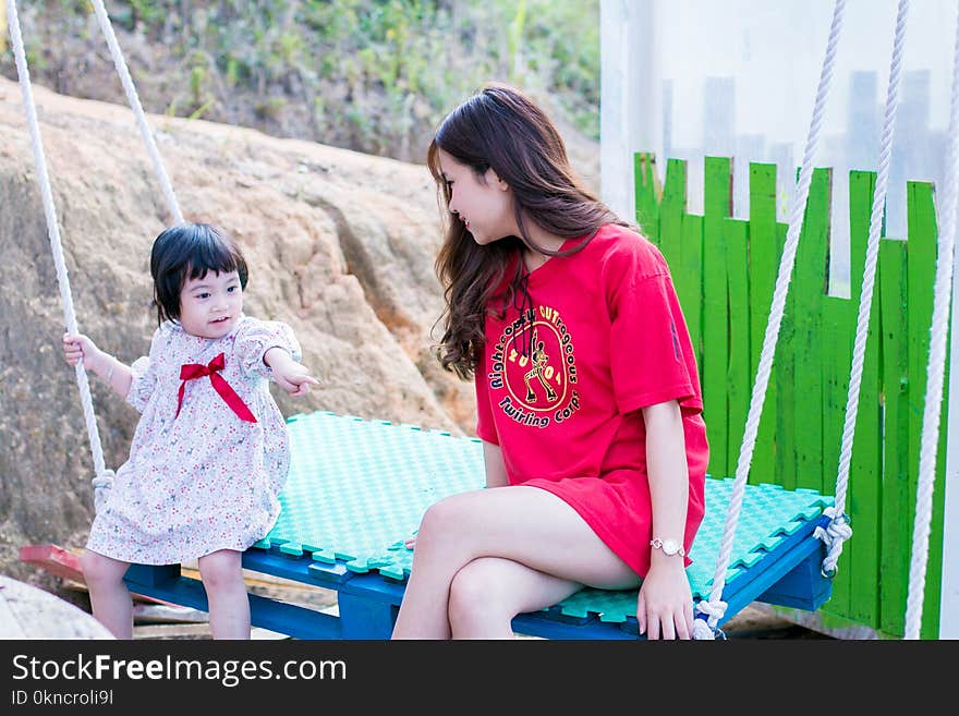 Woman Wearing Red Crew-neck Shirt Sitting on Swing Bench