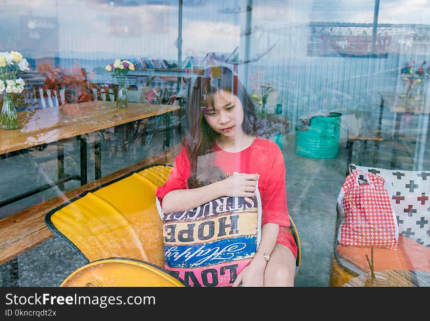 Woman Wearing Red Crew-neck T-shirt Sitting on Yellow Sofa Chair