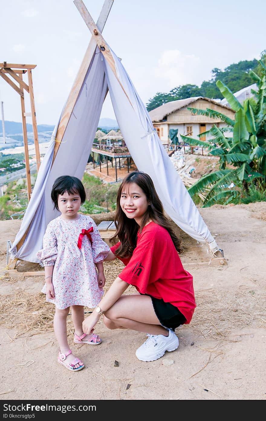 Woman Wearing Red T-shirt Squatting on Front of Gray Tent