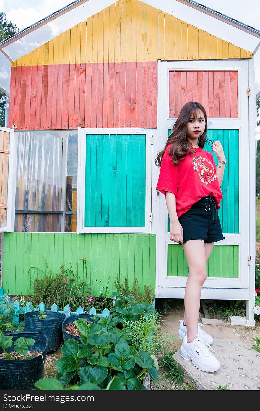 Woman Stands Near Multicolored Wooden House