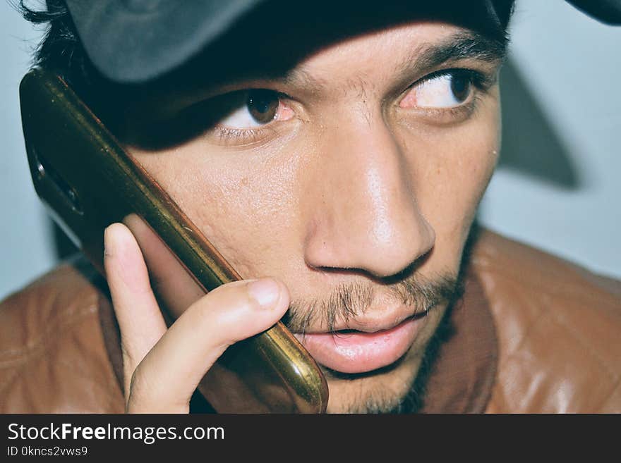 Man Wearing Brown Leather Jacket Holding Black Android Smartphone With Brown Case