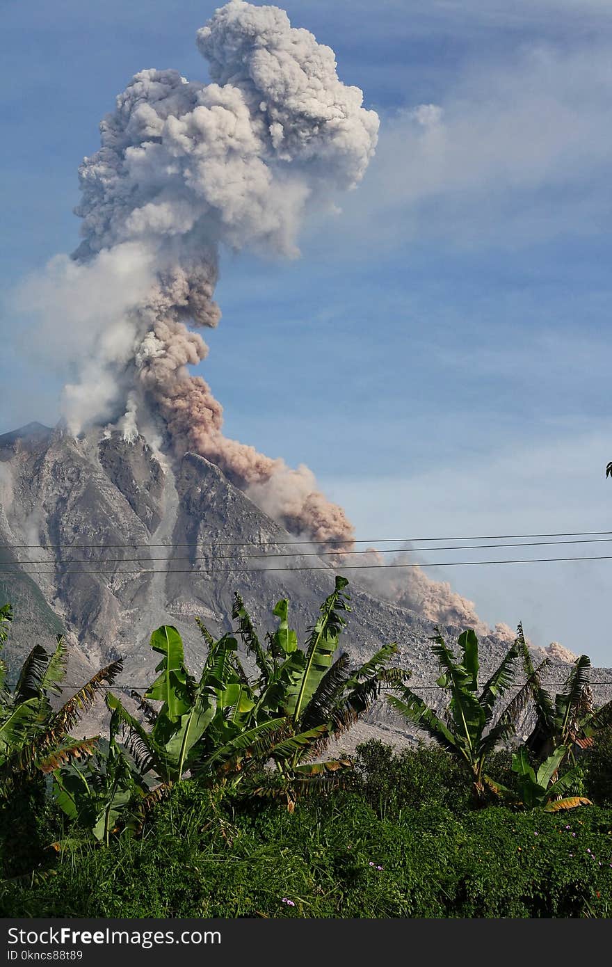 Erupting Volcano Under Blue Sunny Cloudy Sky