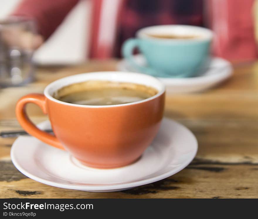 Shallow Focus Photo of Orange Ceramic Mug on White Saucer