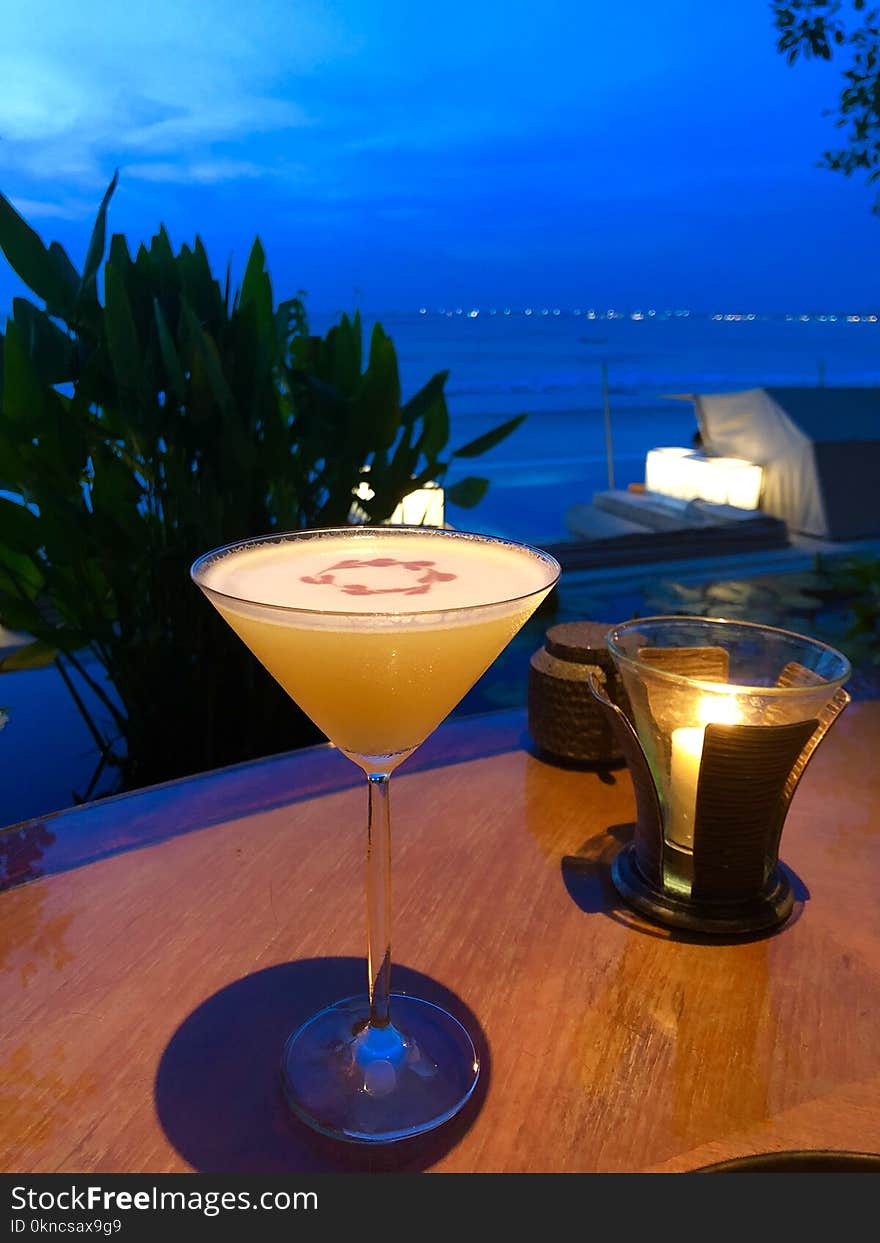 Orange Liquid in Clear Martini Glass on Brown Wooden Surface