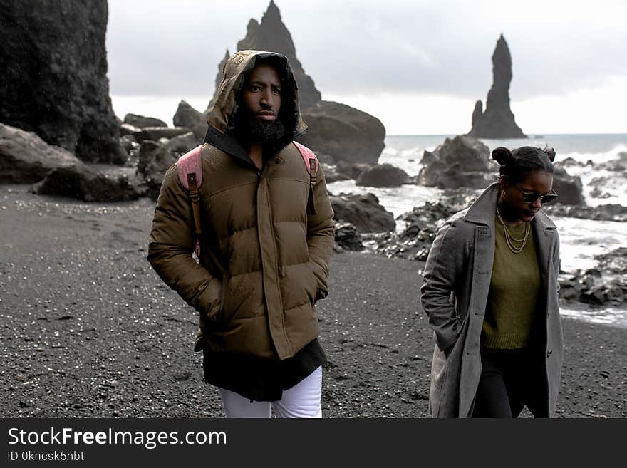 Man and Woman Wearing Jackets Walking on Shore