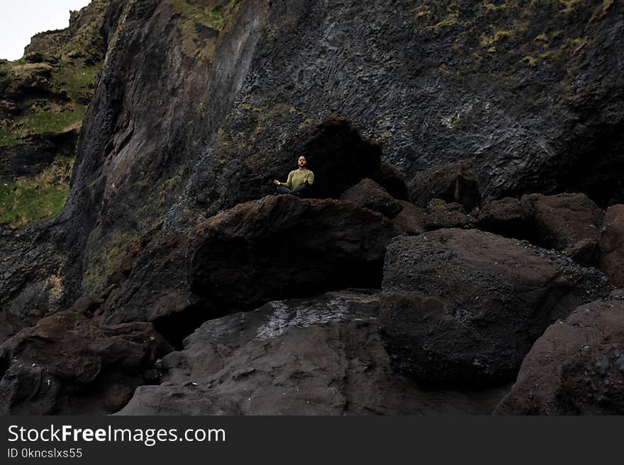 Photo of Person Meditating on Top of Rock