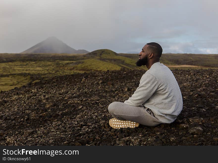 Man in White Top Sitting on Brown Soil