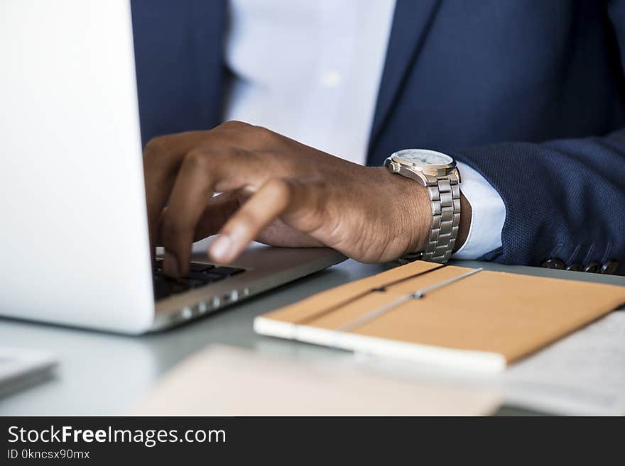 Photo of Person Wearing Gray Analog Watch Tapping Keyboard of Laptop