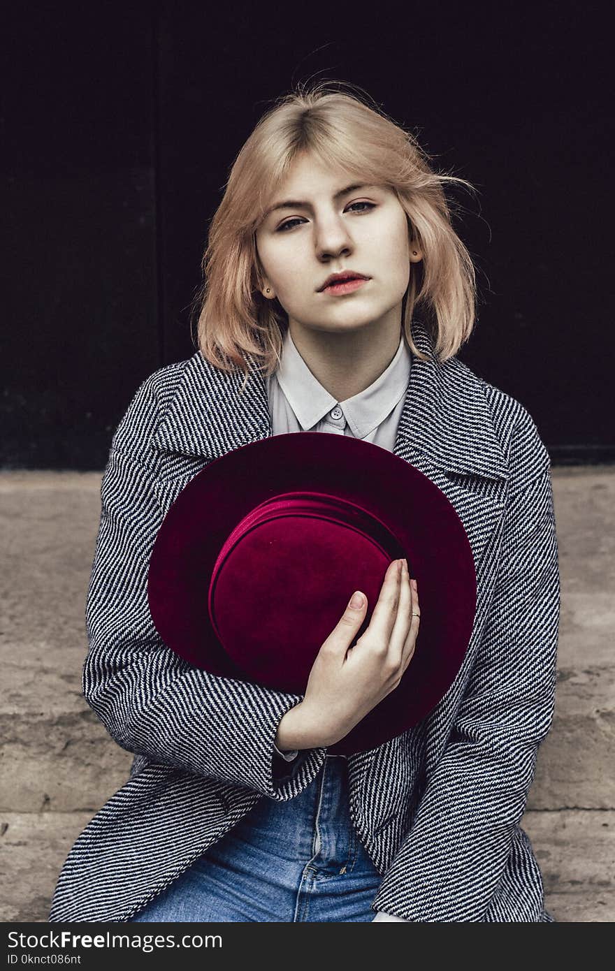 Woman in White Collared Top and Gray Coat Holding Red Fedora