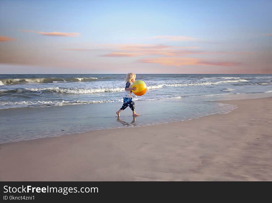 Boy Holding Ball Near Body of Water