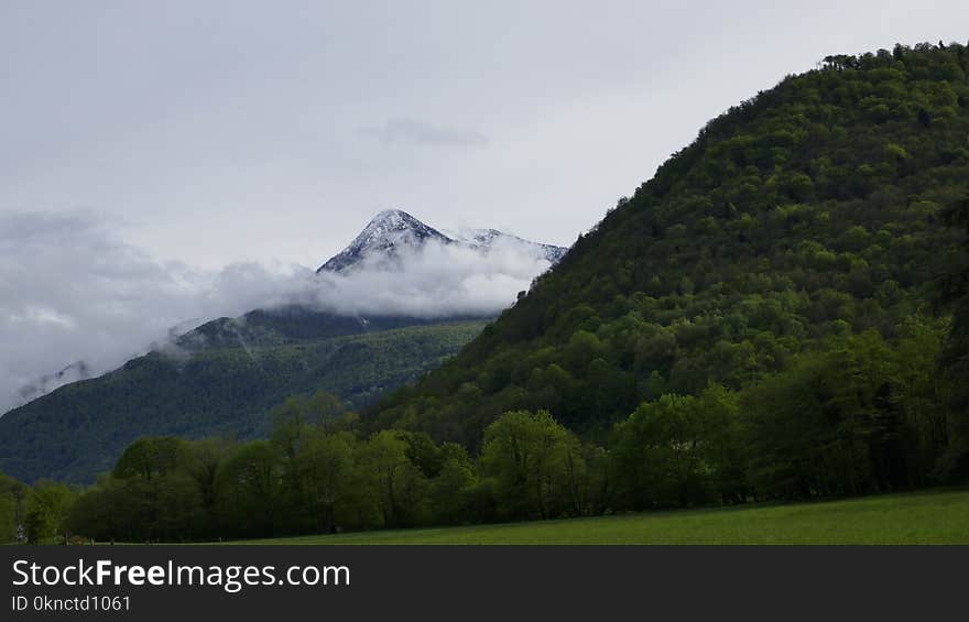 hill next to a mountain Surrounded by Clouds