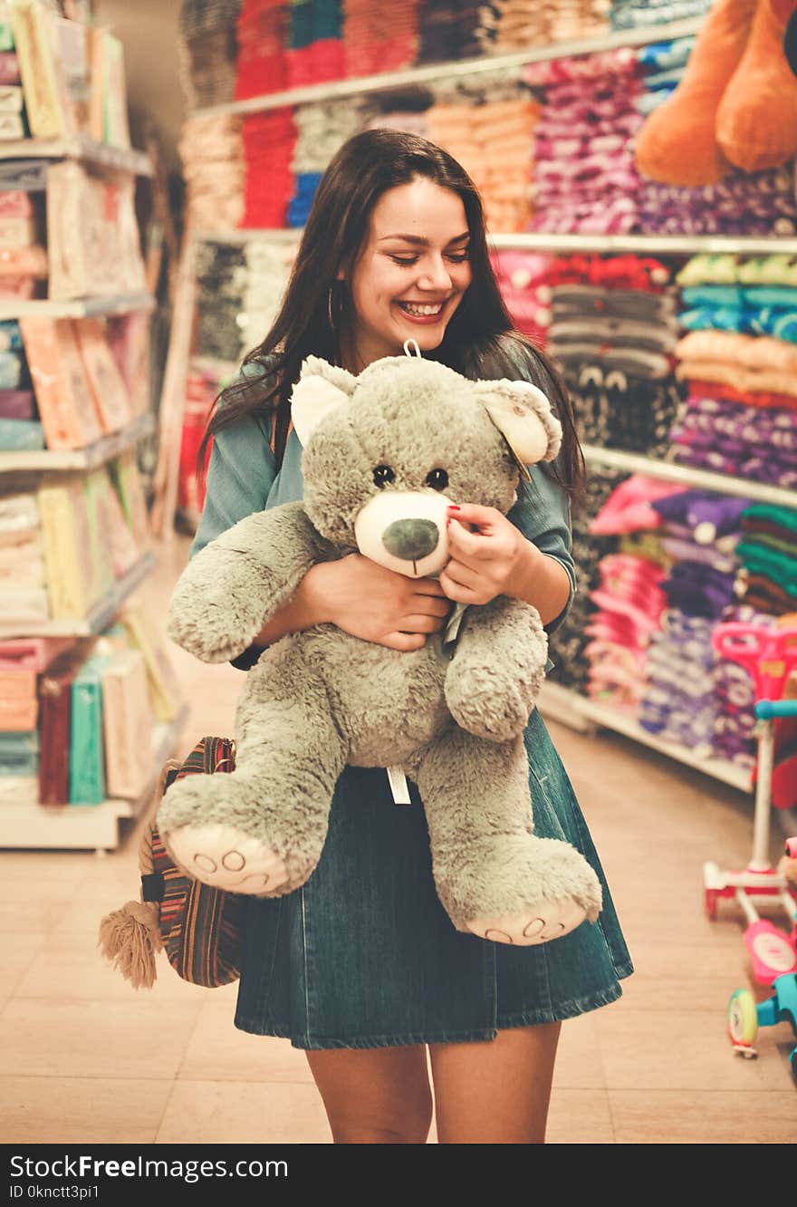 Woman Wearing Blue Top and Blue Denim Skirt Hugging a Brown Bear Plush Toy