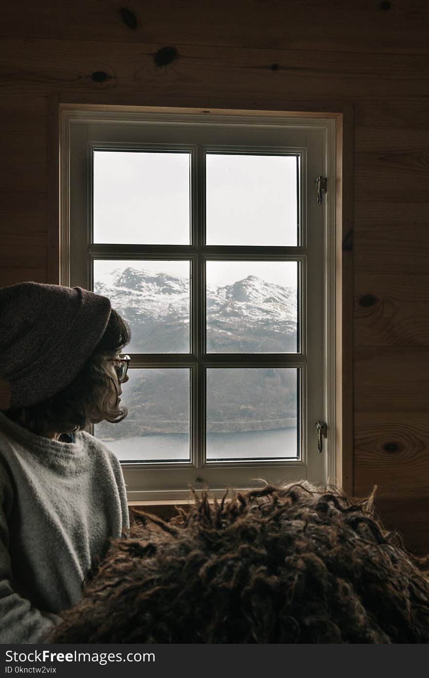 Woman Wearing Grey Sweatshirt and Grey Beanie Sitting Near Windowpane at Daytime