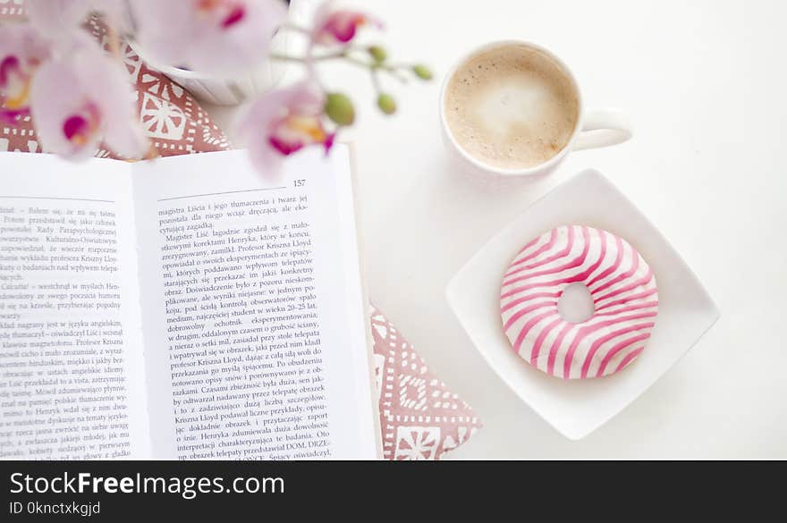 A book, cup of coffee and flavoured donut on Square White Ceramic Bowl