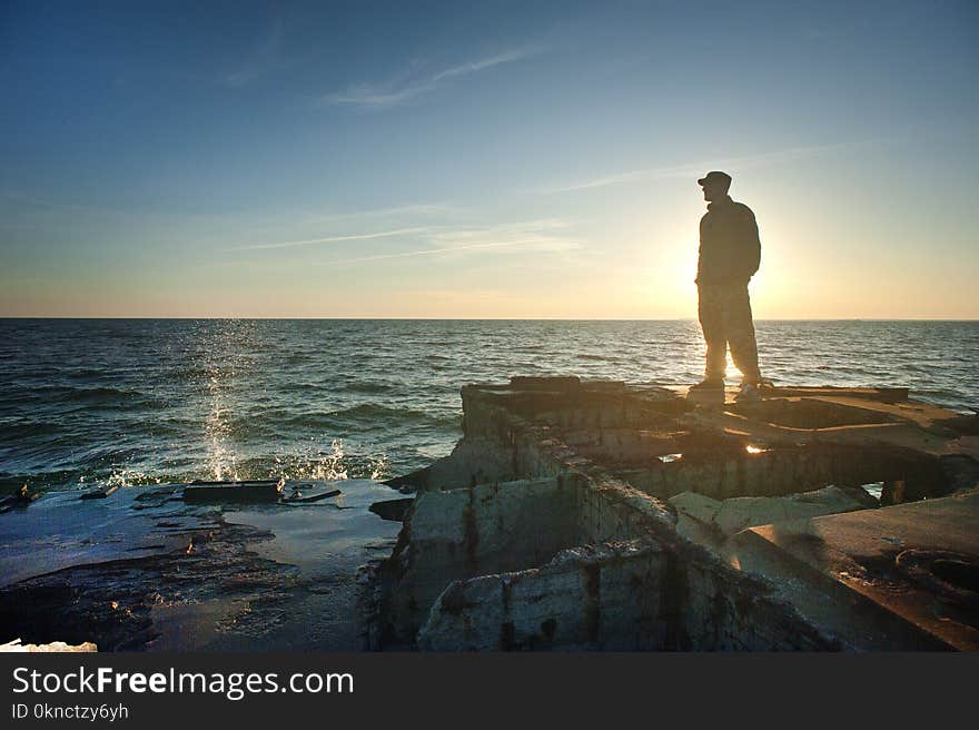 Silhouette Photo of Man Standing Near the Edge of Concrete Pavement