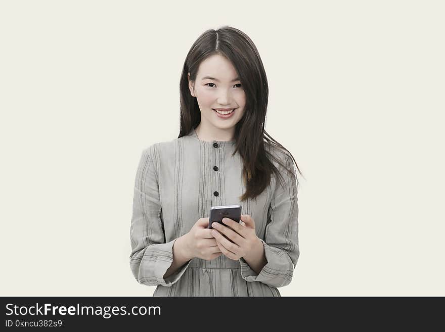 Woman in Gray Button-up Long-sleeved Dress Holding Black Smartphone