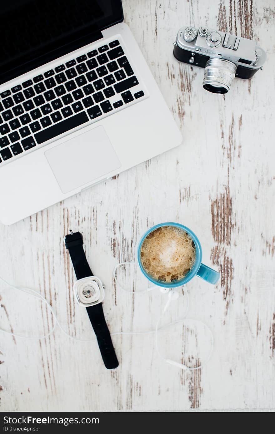 Silver and Black Camera; Silver and Black Laptop; Blue Ceramic Mug